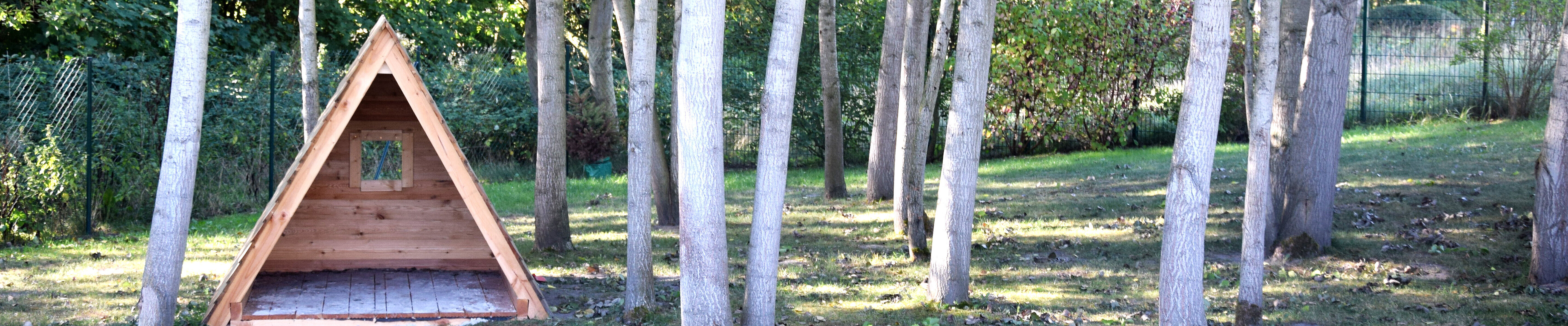 Holztipi unter Birken auf dem Außengelände der Kita