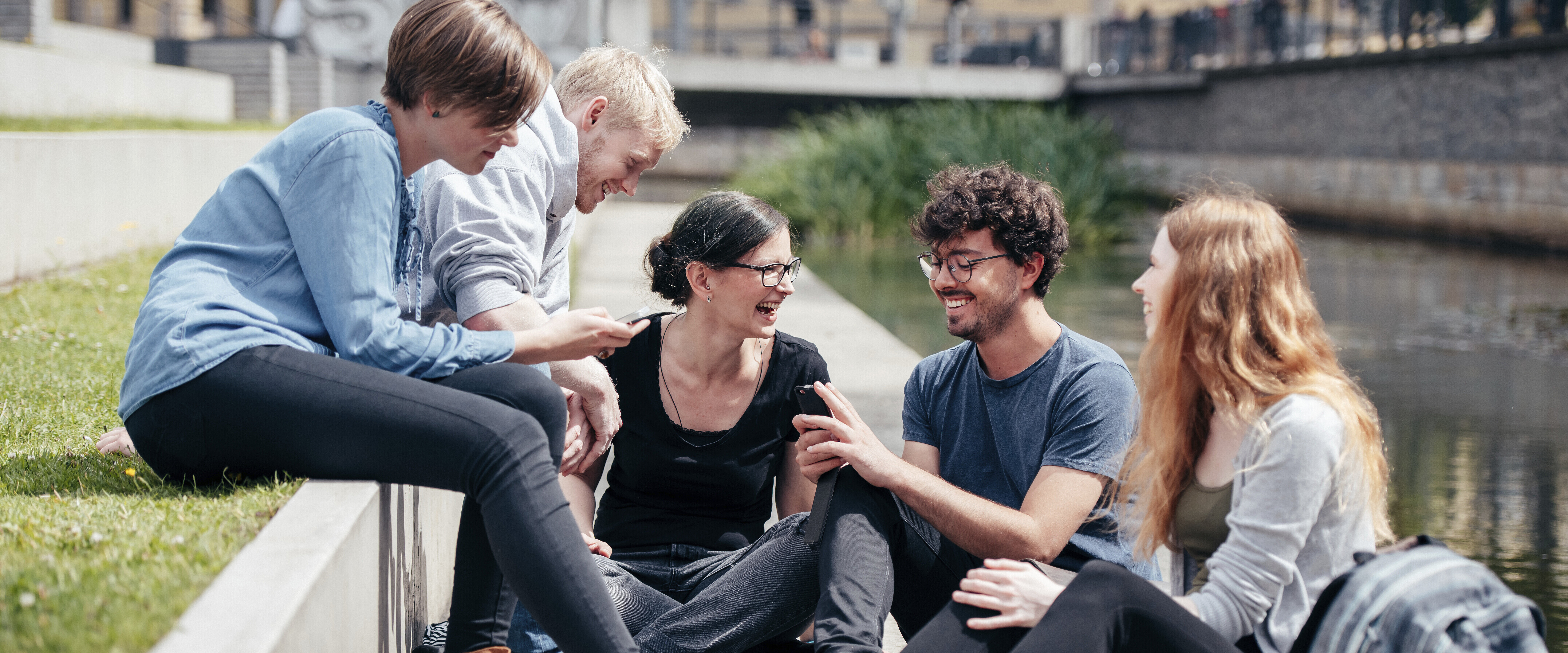 eine Gruppe junger Menschen unterhält sich fröhlich im Freien